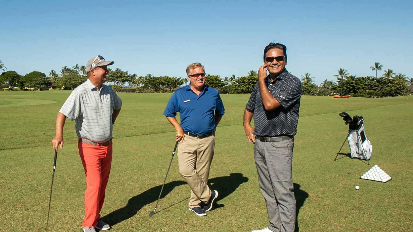 Three Golf pros standing on golf course smiling