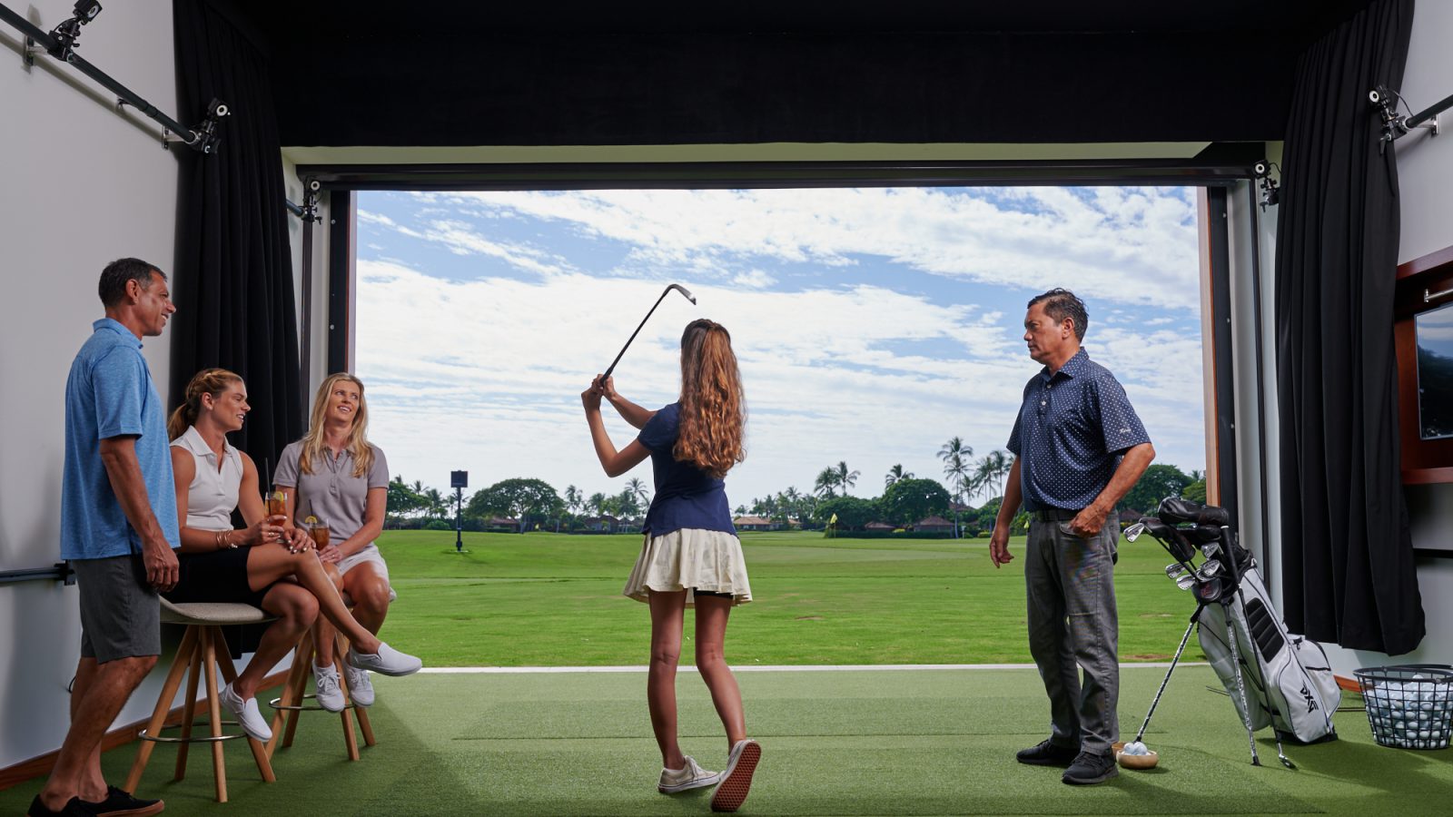 An instructor watches a girl swing while the family of three look on.