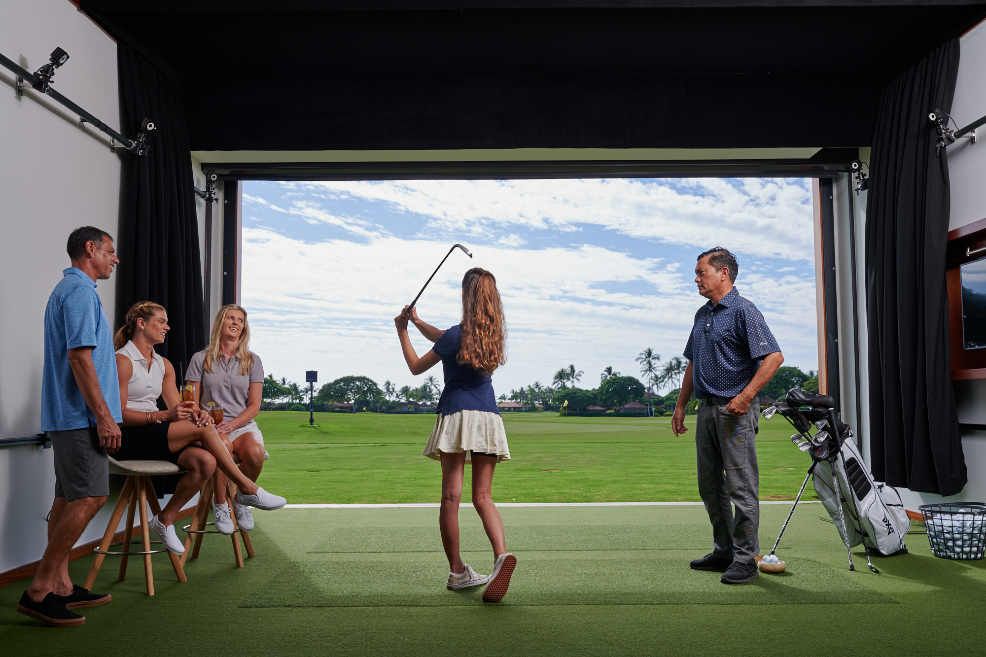 An instructor watches a girl swing while the family of three look on.